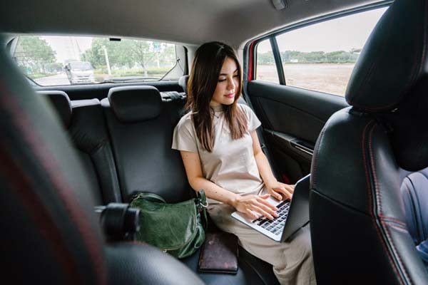 woman working on her laptop in the back of a car